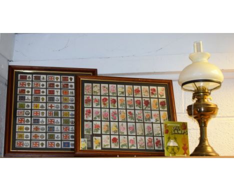 A brass oil lamp; a book, Discovering Oil Lamps; a framed set of cigarette cards, regimental standards and cap badges; anothe