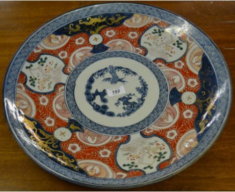 An early 19th Century Japanese ceramic charger, colours from the Imari palette, with gilt highlights and painted four charact