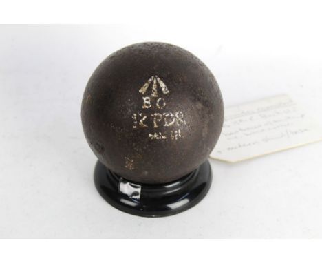 A 12 lb cannon ball, marked to front with broad arrow with BO below and 12 PDR mounted on a stand.  Diameter +/- 12 cm.