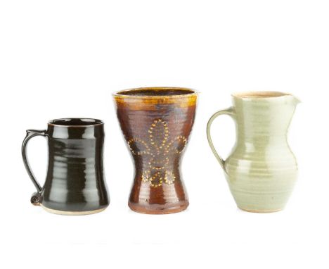 Leach Pottery An early mugtreacle glaze with fleur-de-lis decoration18cm high; and a Leach Pottery jug and mug (3). Provenanc