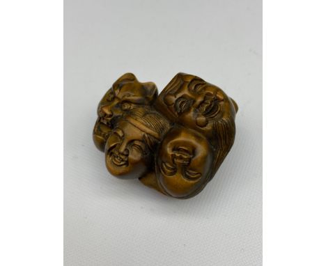 A Japanese hand carved netsuke of 7 Oni masks clustered together. Signed. [4.5cm at widest point] 