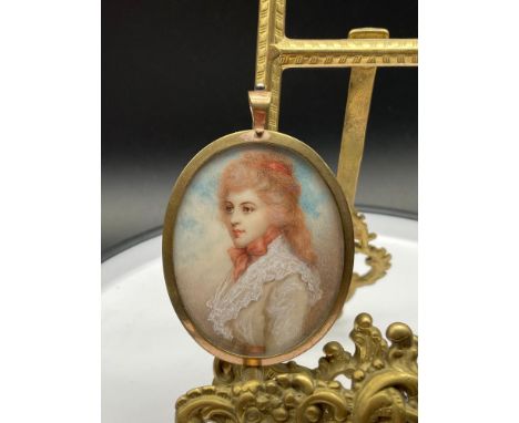 A Victorian brass bound pendant. Encased is a hand painted portrait on ivory of a lady. 