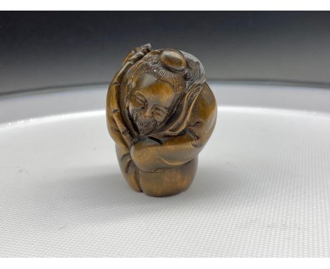 A Japanese hand carved netsuke of an older gentleman carrying fish on his back. Signed to the base. 