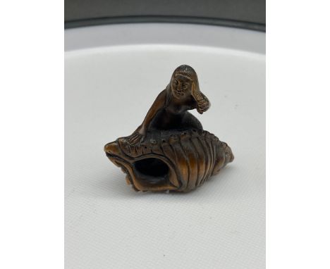 A Japanese hand carved netsuke of a mermaid sat upon a large shell. Signed. [4.5cm in length] 