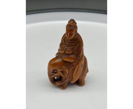 A Japanese hand carved netsuke of a Thai god figure riding an elephant. Signed. [5.5cm in height] 