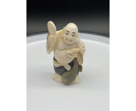 A Japanese Meiji period ivory carved netsuke of a laughing buddha holding a rat. [7cm in height] 