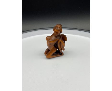 A Japanese hand carved netsuke of a semi nude geisha woman. Signed to the bottom of her robe. 