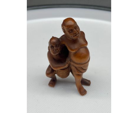 A Japanese hand carved netsuke of two men wrestling. Signed. [5cm in height] 