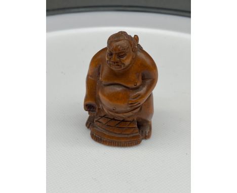 A Japanese hand carved netsuke of a sumo wrestler, signed. [5cm in height] 