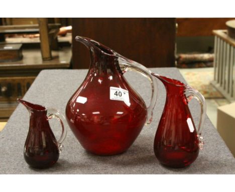 Three graduating ruby red Whitefriars jugs with reeded handles.