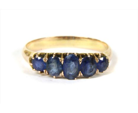 A gold five stone sapphire ring, with a row of graduated oval mixed cut and round mixed cut sapphires, claw set to tapered sh