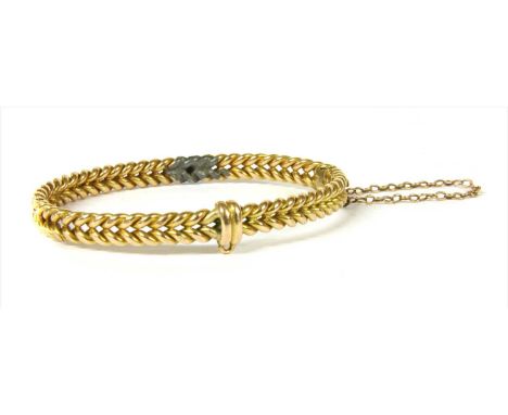 A gold oval hinged bangle, two rows of twisted wire to concealed box clasp and safety chain, tested as approximately 9ct gold