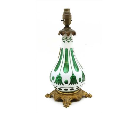 A Bohemian overlaid green white glass lamp, of bulbous form, on a gilt metal base, 32cm high