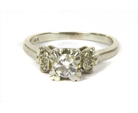 A white gold diamond ring, with a brilliant cut diamond claw set to a square collet, to crescent shaped shoulders, grain set 