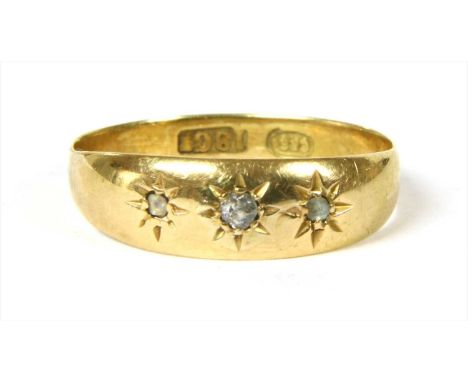 A gold three stone diamond ring, with a Swiss cut diamond with smaller rose cut diamond at each side, all star set to a taper