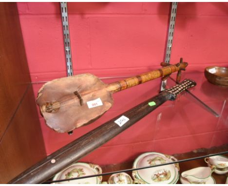 A tribal club, the handle inlaid with mother of pearl; together with a tribal stringed instrument, partly formed from a turtl