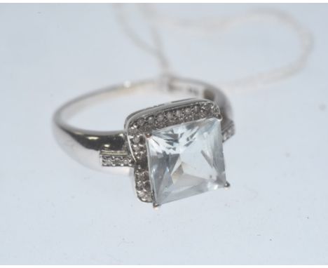 An aquamarine and diamond ring, the square cut aquamarine within a bezel of diamonds on diamond set shoulders and mounted in 