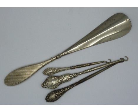 Three silver handled button hooks and a silver handled shoe horn