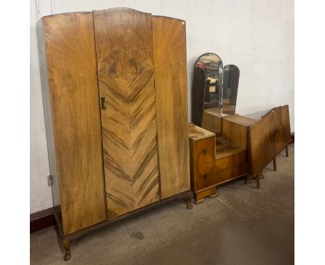 An Art Deco figured walnut bedroom suite, comprising; dressing table, wardrobe and headboard