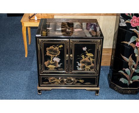A Chinoiserie Decorated  black lacquered cabinet with gilt highlights and landscape decoration. Two doors to front over a sin