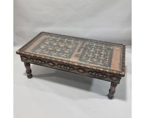 An ornate Moroccan centre table, made from an Antique studded and metal inlaid door behind a glass panel, with elaborate inla