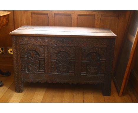 A Charles I oak coffer, with plank lid, the front with 3 panels each carved with a vase of flowers within an arch beneath a c