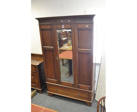 An early 20th century oak wardrobe, the oversailing ogee cornice carved with scrolling acanthus to frieze, central mirrored d