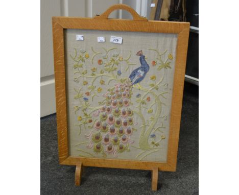 A mid 20th century oak firescreen, embroidered with peacock and floral scroll. 