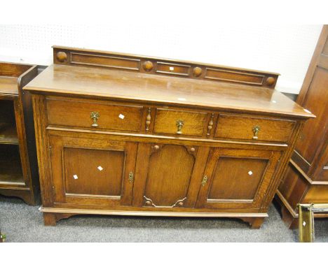 An early 20th century oak sideboard, the super structure with pronounced circular inclusions, projecting base enclosing three
