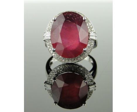 14ct white gold ring 
set with a 15ct oval ruby and small diamonds (approx. 1ct total), setting height 19mm, size M.