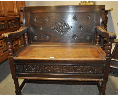A carved and panelled oak monks bench,
raised on bobbin turned legs, width 3'3".