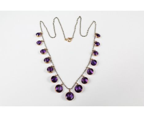 An Edwardian Graduated Amethyst Necklace. The necklace set with fifteen graduated amethysts ranging from 6mm to 10mm, on a si