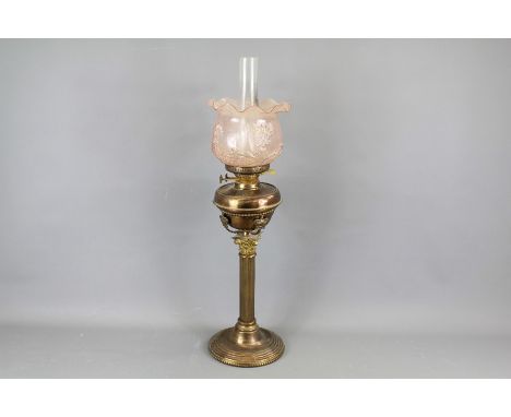A Victorian Oil Lamp. The lamp having a glass fluted pink shade with floral decorations, Corinthian column base, measures app