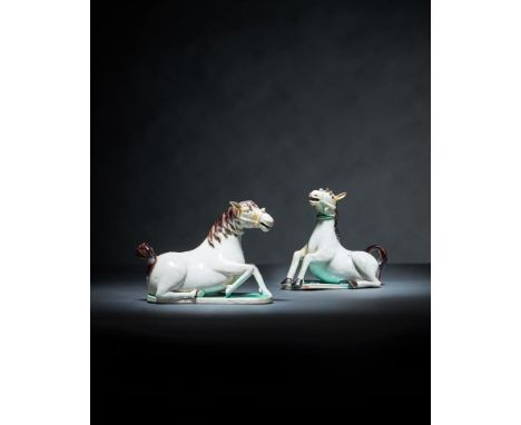A rare pair of Chinese white glazed figures of horse water droppers, Kangxi, shown recumbent on shaped bases, with brown glaz