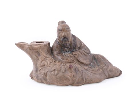 A Chinese yixing water dropper, 19th century, moulded in the design of a scholar leaning on a tree trunk with a recumbent goo