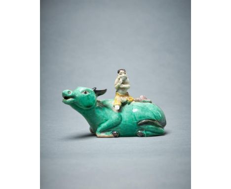 A Chinese biscuit glazed water dropper model of a boy seated on a buffalo, Kangxi, glazed in green and yellow with black deta