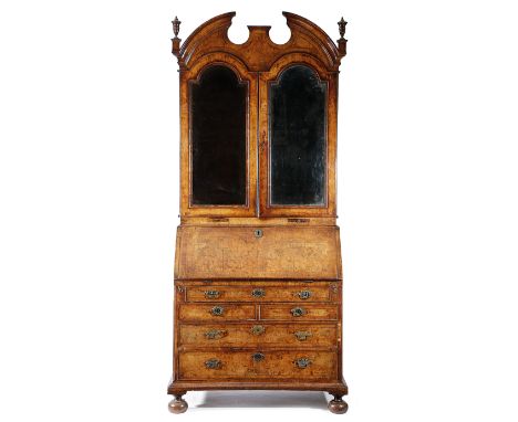 A GEORGE II WALNUT BUREAU BOOKCASE C.1730 cross and feather banded, the broken arch cornice with turned finials, above a pair
