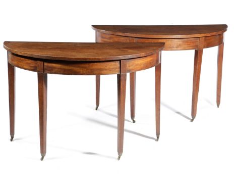 A PAIR OF GEORGE III MAHOGANY DEMI-LUNE CONSOLE TABLES POSSIBLY IRISH, C.1780-90 each on square tapering legs and brass casto