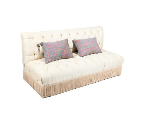 A CREAM UPHOLSTERED BUTTONED BANQUETTE  OF RECENT MANUFACTURE  The button upholstered back above a conforming seat, the taper