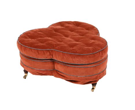 A RED VELVET UPHOLSTERED OTTOMAN STOOL  OF RECENT MANUFACTURE Of 'trefoil' outline, on turned tapering legs with brass castor