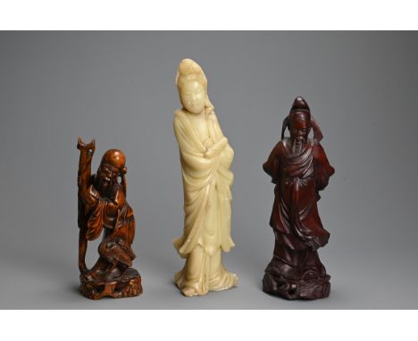 THREE CHINESE CARVED WOOD AND SOAPSTONE FIGURES, 20TH CENTURY. To include a carved jade figure of standing Guanyin; A carved 