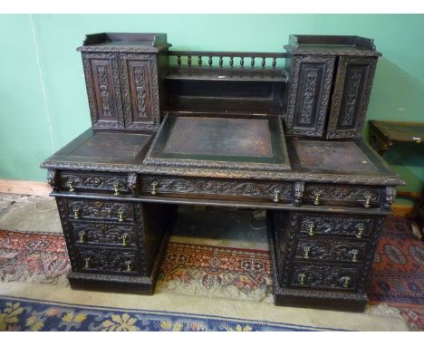 A 19th c. oak Dickens style Kneehole Desk, the top having two, two door cabinets joined by a galleried shelf, central slope r