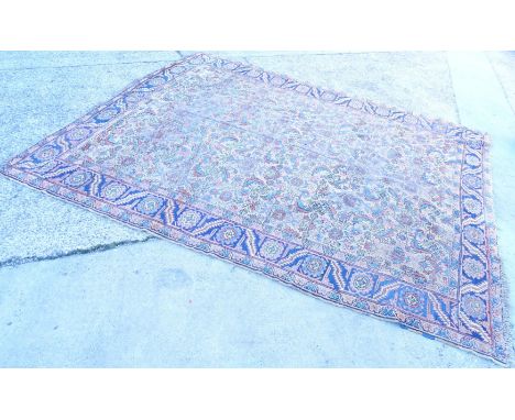 A Persian carpet, with an all over geometric design on a deep beige ground within multiple borders, 277cm x 343cm.