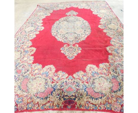 A large Kirman carpet, with a central medallion on a red ground, with floral borders and spandrels, 410cm x 297cm.