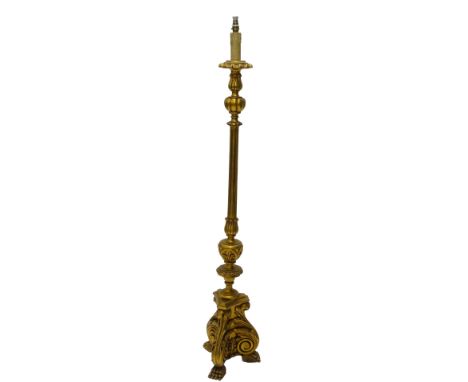 A gilt standard lamp in Continental style, with a fluted column and tri form base with paw feet, with a silk type shade.