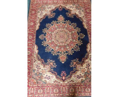A machine woven wool carpet, in Persian style with a central floral medallion and multiple borders.