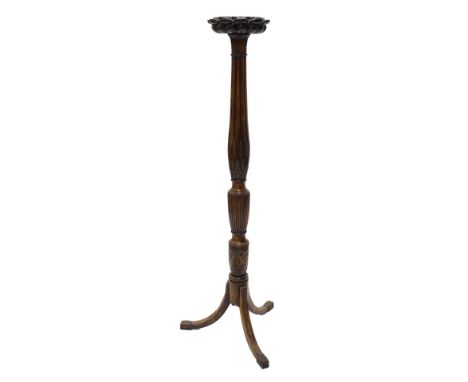A mahogany torchere, the circular top with a lappet carved border on a part reeded and fluted column decorated with wheat ear