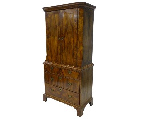 A late 19thC/early 20thC Dutch walnut and feather banded cabinet, the top with a moulded cornice above two doors enclosing ad