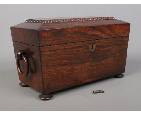 A 19th century rosewood tea caddy of sarcophagus form. Having twin loop handles, fitted interior with cut glass mixing bowl a