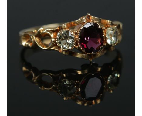 A 19th century gold three stone ring with chased decoration to band. Having central ruby coloured stone flanked by two clear 